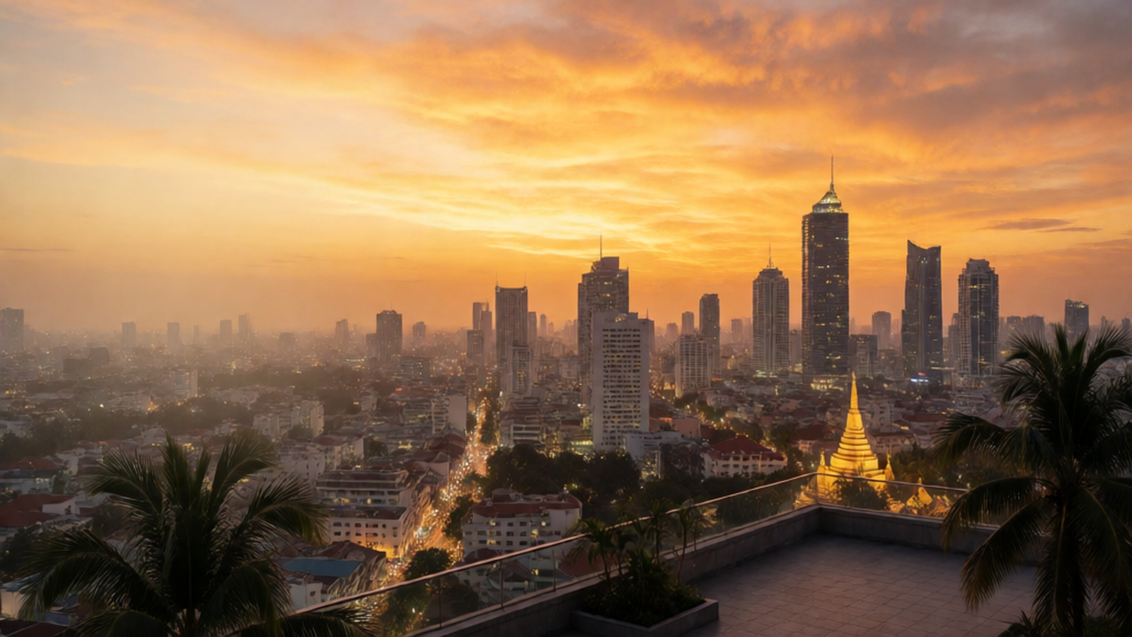 Digital nomad working beside a window overlooking a tropical city at golden hour